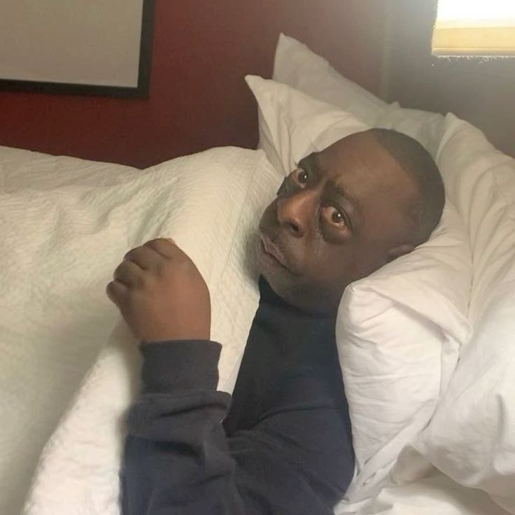 a man laying in bed with his arm up