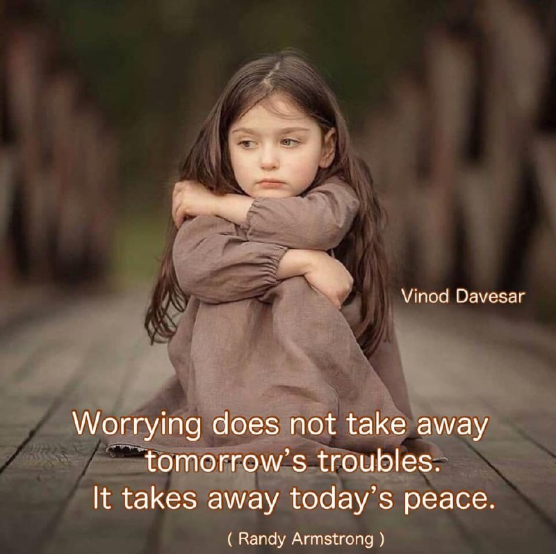 a little girl sitting on a wooden floor with her arms crossed